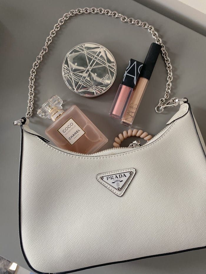 Elegant flatlay featuring a luxury handbag with makeup and perfume.